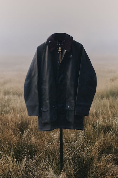 Barbour coat stands on a stick in a field.
