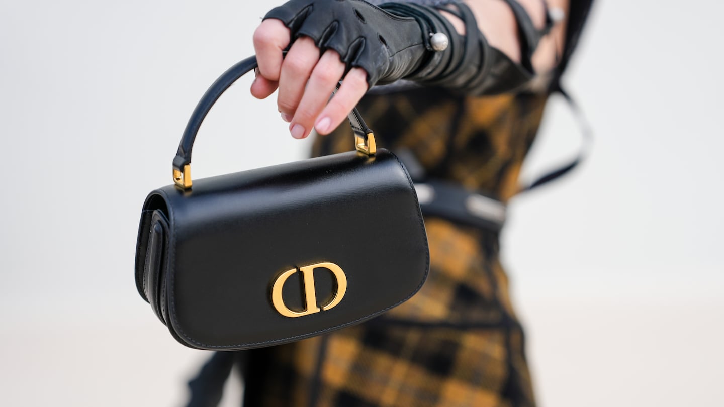 Woman holding a black Dior purse with gold hardware
