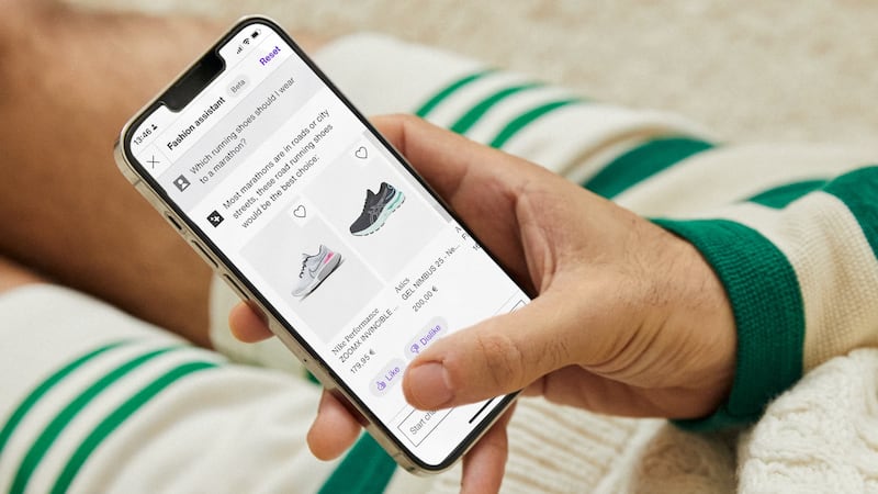 A person holds a phone and shops using the Zalando virtual assistant. They have asked the chatbot which shoes are the best for a marathon and the chatbot has made suggestions.