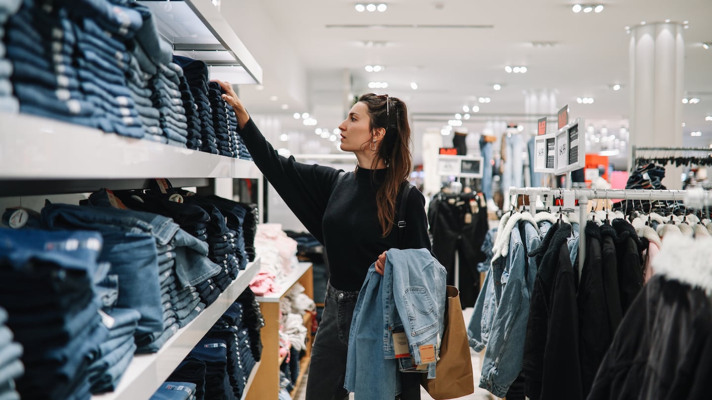 Woman shopping through denim pants piles.