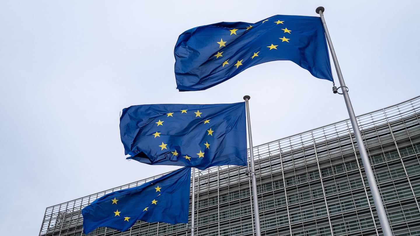 Three EU flags fly in front of a building.